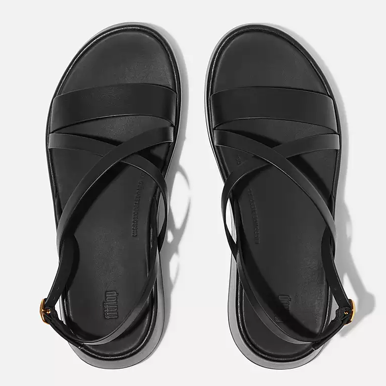 Black leather slingback crisscross sandal with low wedge and gold adjustable buckle. 
