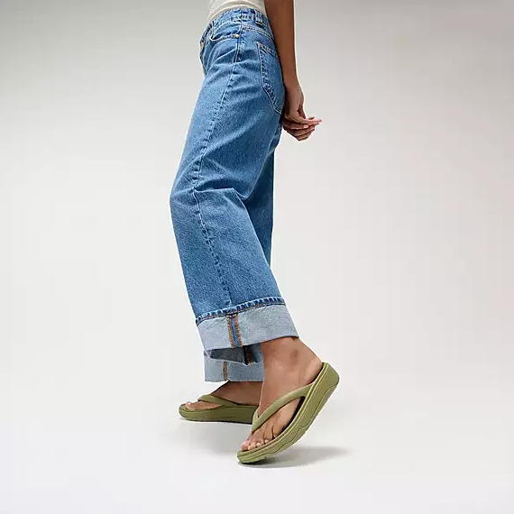 Muted green toe-post flip-flop sandal with low platform on a person.