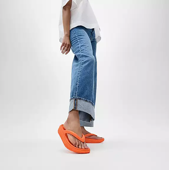 Bright orange toe-post flip-flop sandal with low platform on a person.